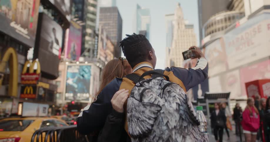 Man and woman take a picture of themselves in the downtown of a city
