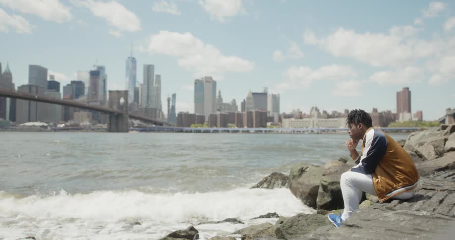 A man sits on the rocks by the crashing waves