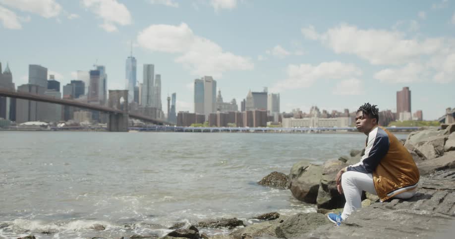 A man sits relaxing by the shore viewing the city