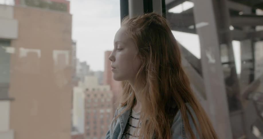 Woman rides in a train in a city looking out the window