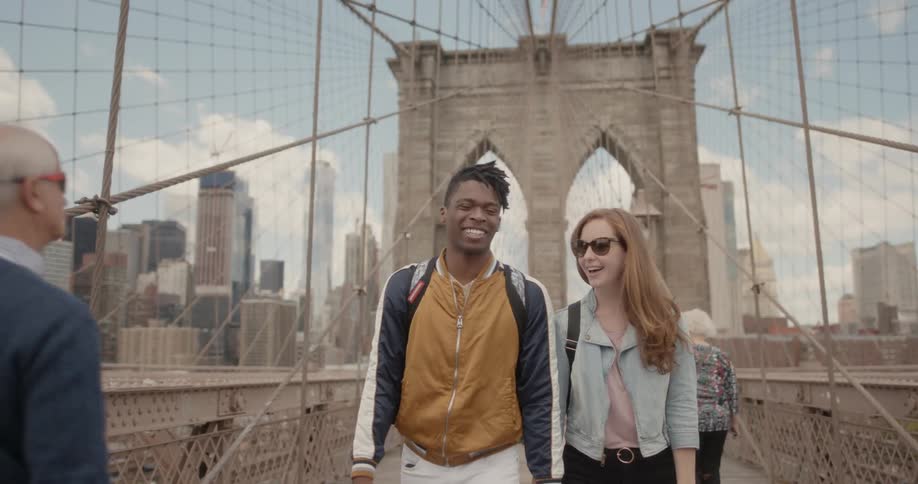 A couple holds hands as they walk across a bridge
