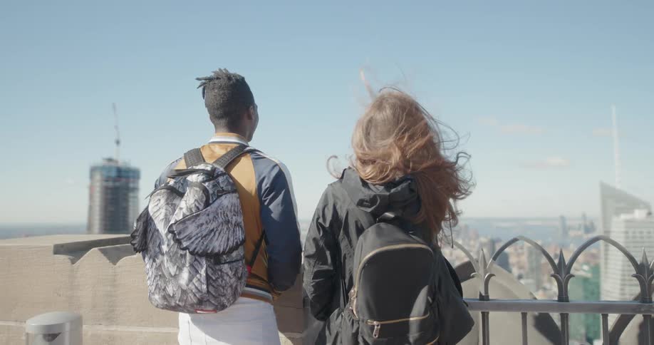 A man and woman take in the view from the windy rooftop