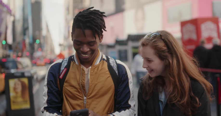 Man and woman smile and take a picture of themselves in the downtown of a city