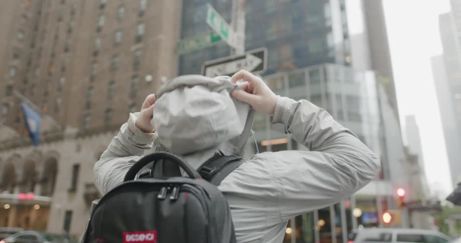 A man stops at the intersection to put his hood on
