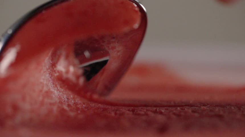 A spoon is scooping through a sorbet or fruit