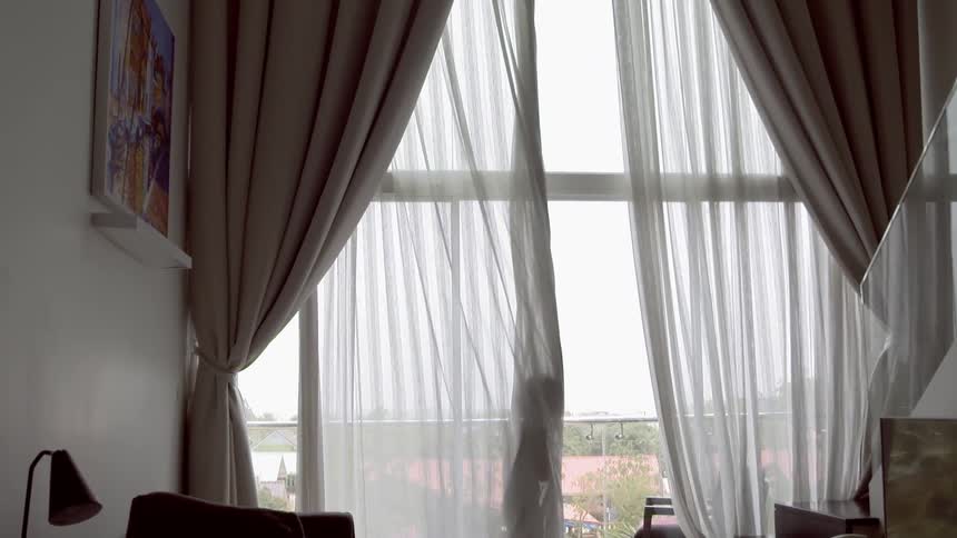 A young child plays inside of curtains