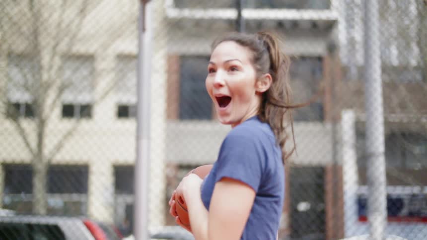 A woman turns around after catching a basketball