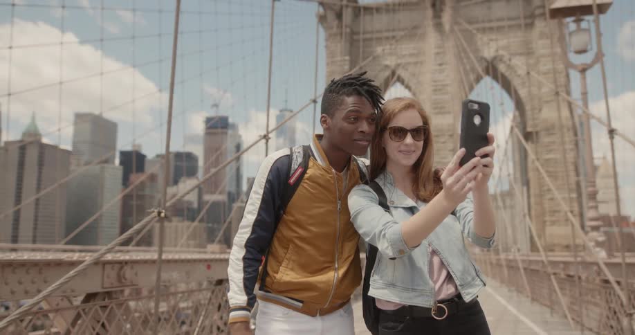 A woman takes a selfie with a friend on the bridge