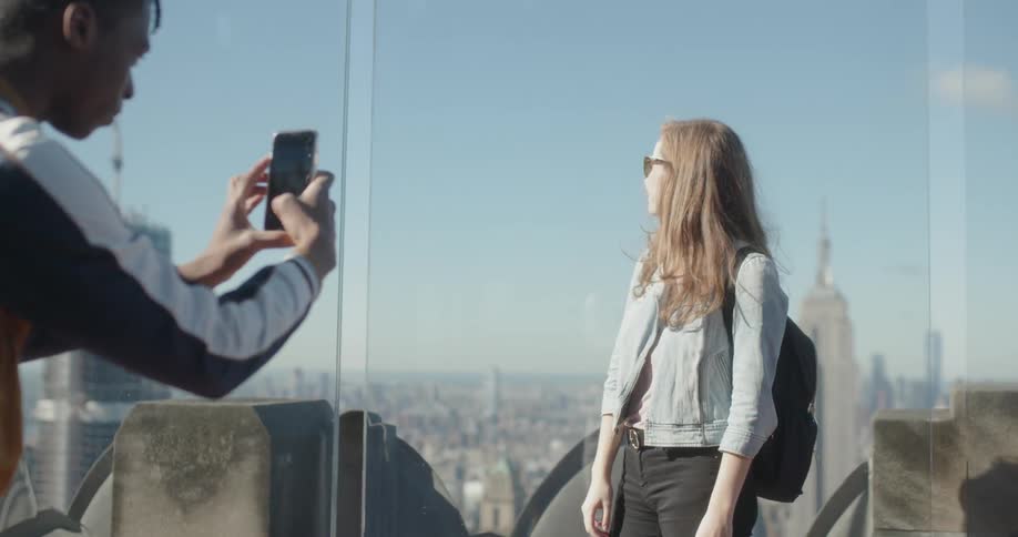 Man takes picture of woman standing on top of building