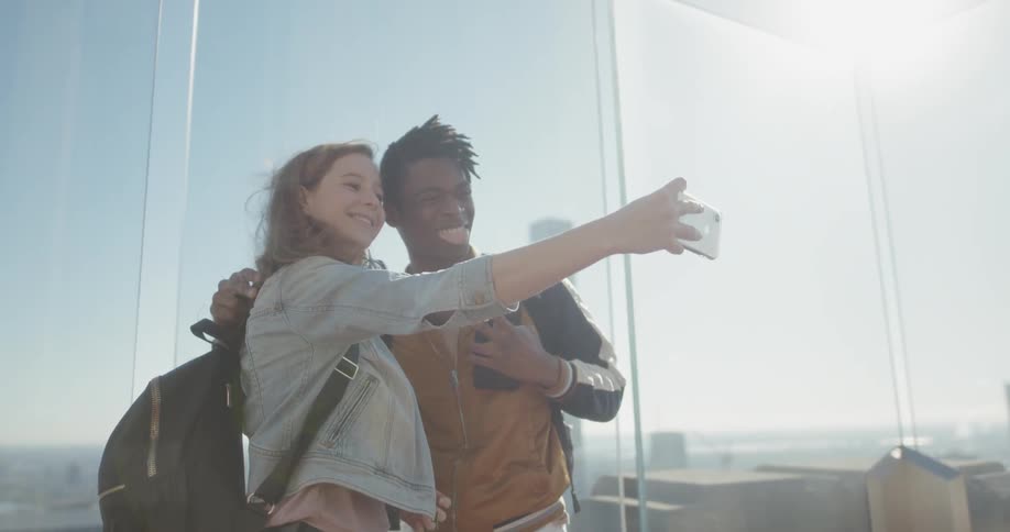 A woman shows her phone to a man on the rooftop