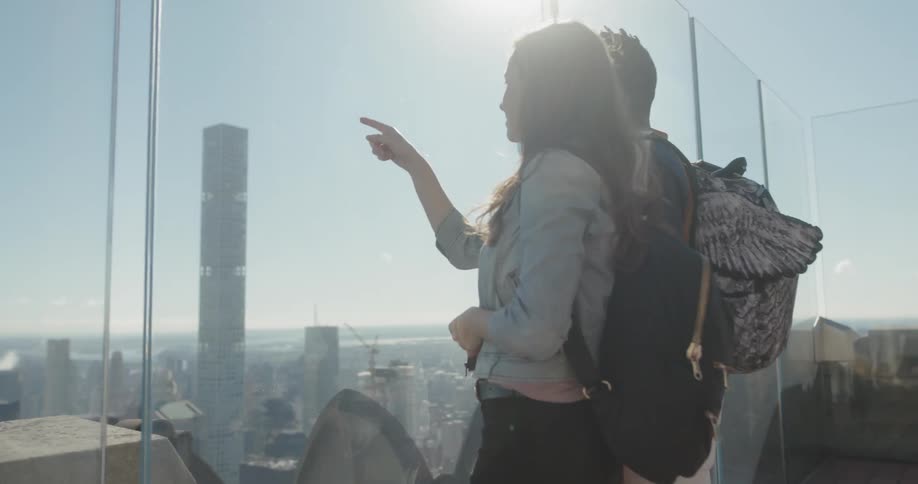 Man and woman on rooftop looking out window and pointing