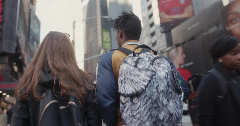Two people walk past crowds in the city