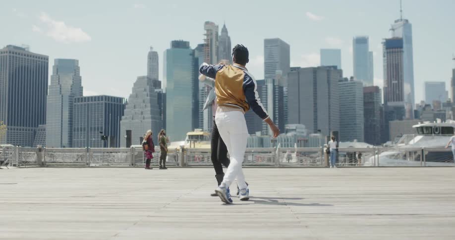 Man and woman dance in a square in a city on a sunny day