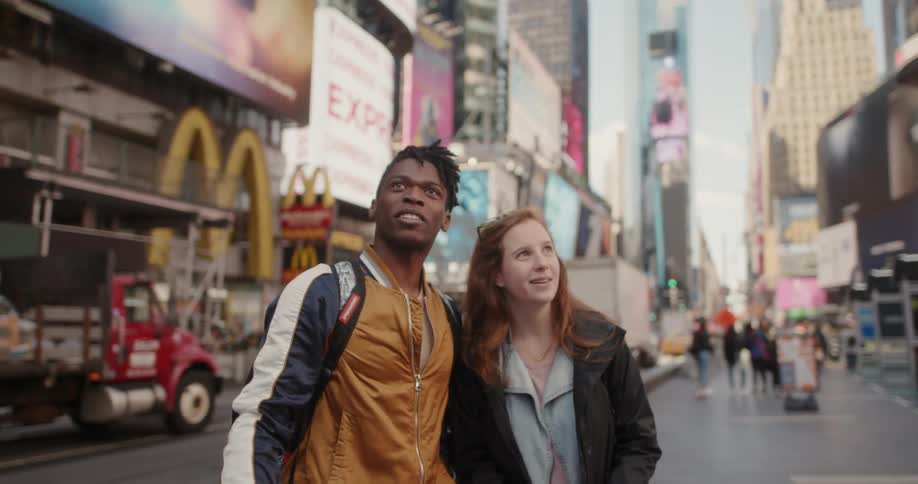Man and woman smile and look around on a city street