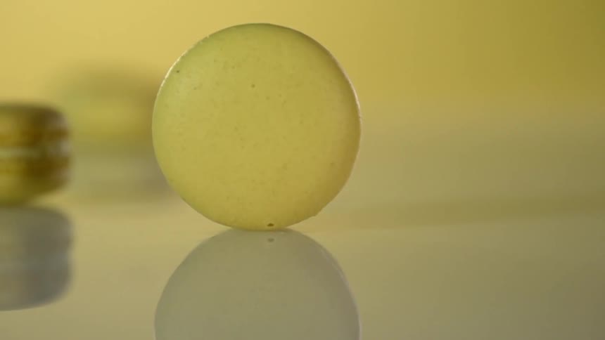 A french macaroon cookie rolls on a shiny countertop