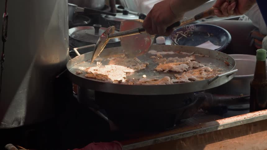 A person is using two spatulas to mix the food on the pan