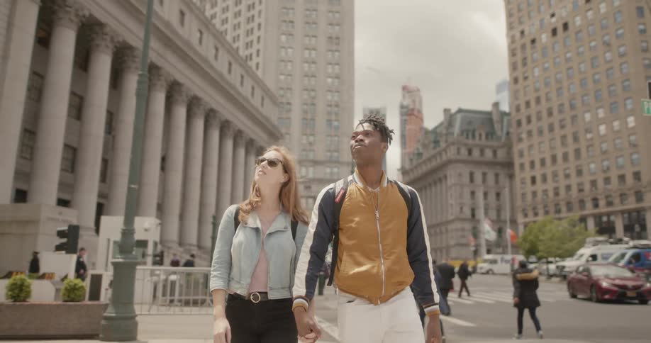 A man and woman walk holding hands in the city