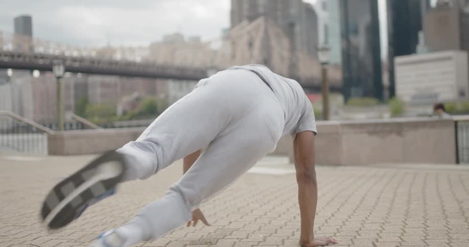 Man break dances beside urban river