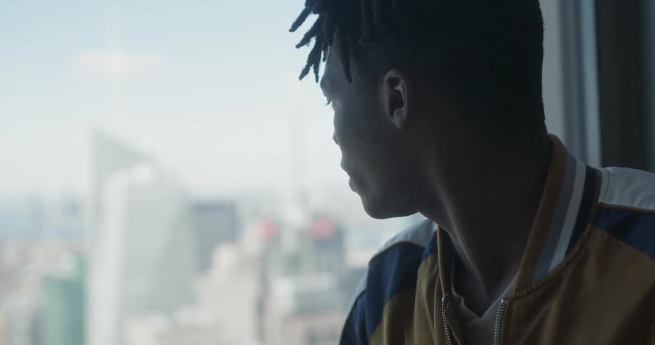 A man looks out at the city buildings on a sunny day