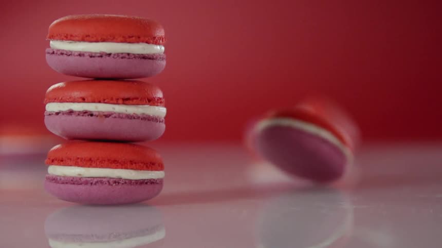 A macaroon is spinning on a surface near a stack of macaroons