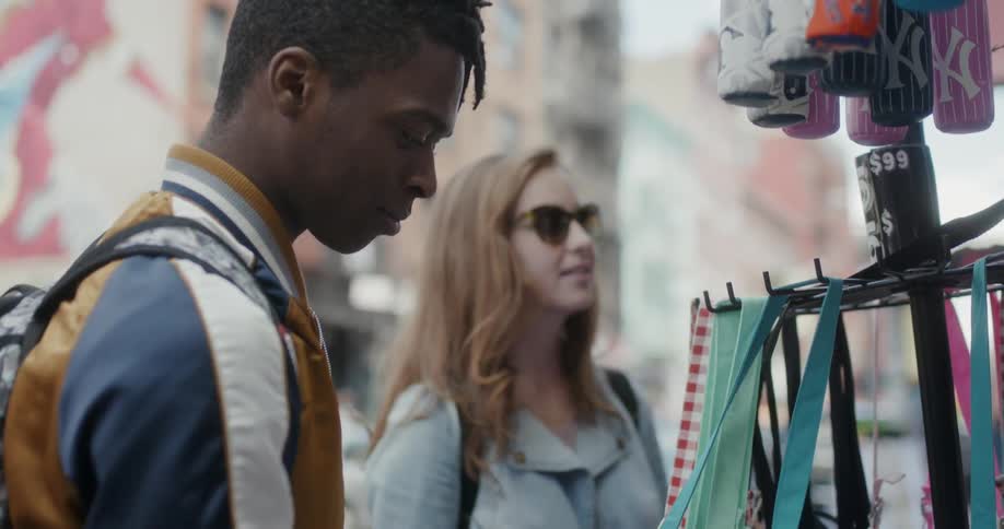 Man and woman look at items on urban sidewalk