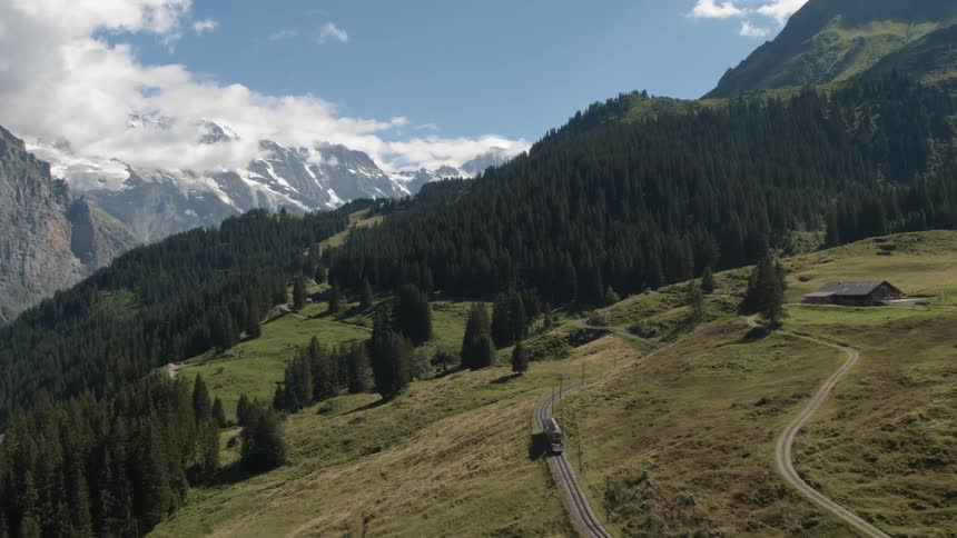 The vehicle travels up the road on the green hill