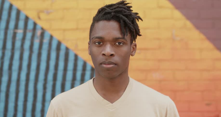 Man stands in front of a brick wall and stares ahead