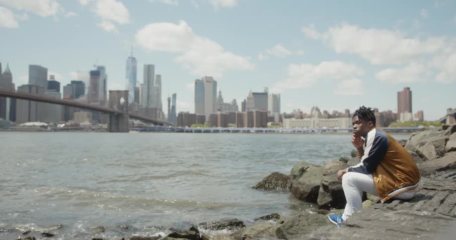 A man sits by the water looking over the city