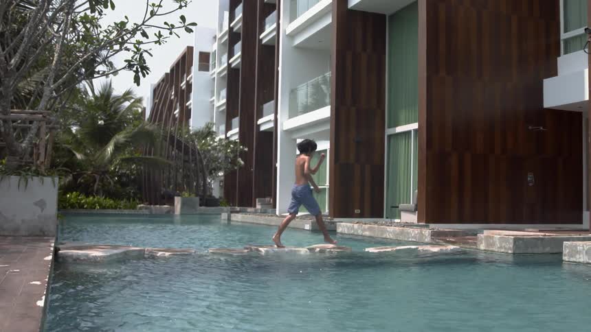 A child climbs over the lip of the pool by the home