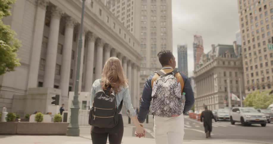 A couple holds hands as they walk down a city street