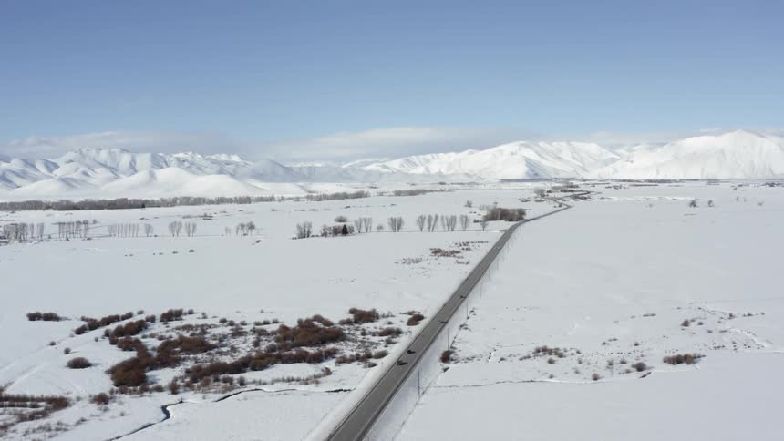 Cars travel on the highway going through the snow covered fields