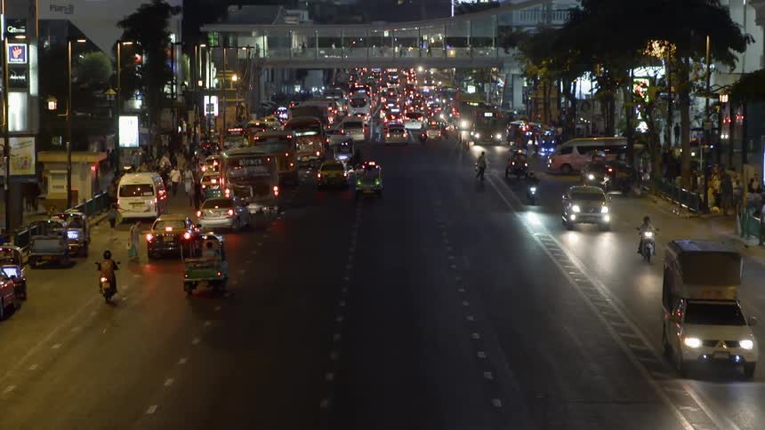 Many vehicles drive down a busy city street at night