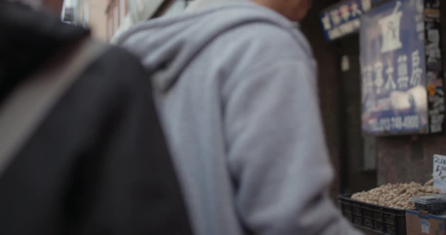 Women with backpacks walk along crowded urban sidewalk