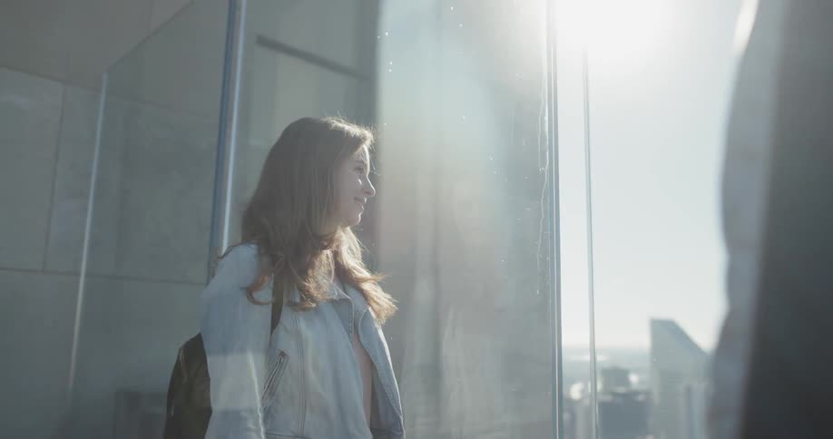 A woman is looking out the window from high in a building
