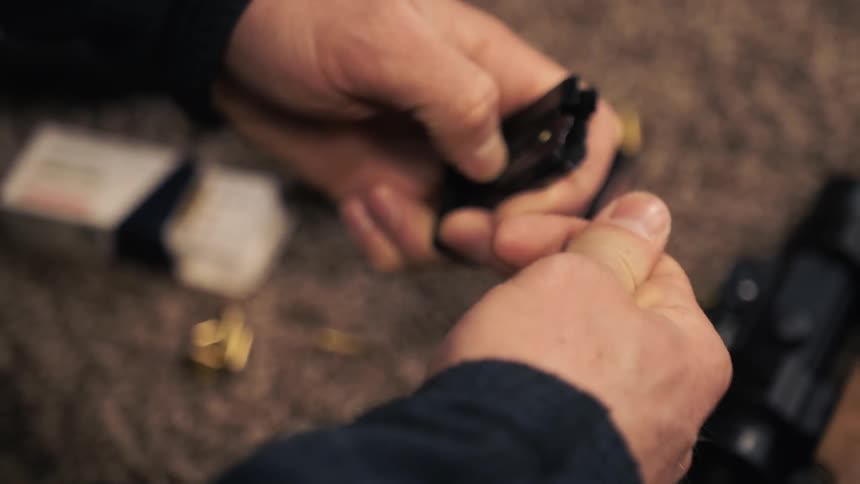 A person puts bullets into a gun clip