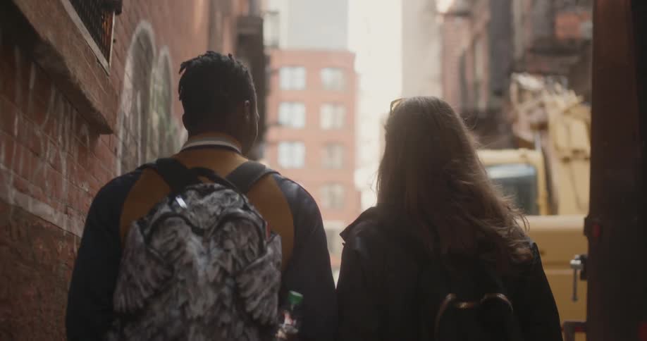 Man and woman with backpacks walk down a city street