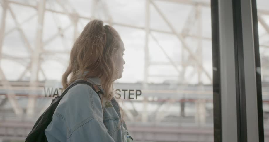Woman looks out a large glass window at a bridge