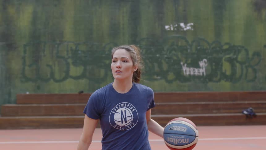 A woman dribbles a basketball on an outside court