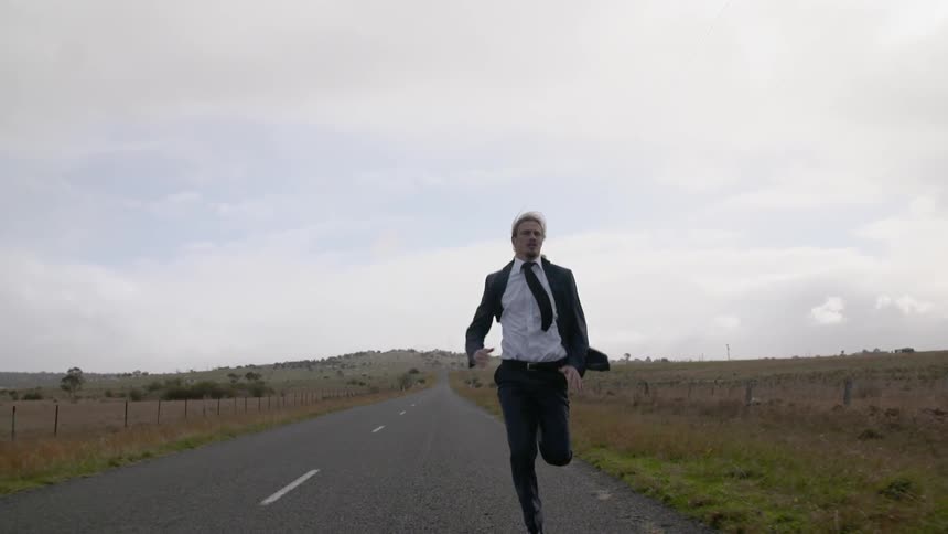 A man in a black suit races down the road