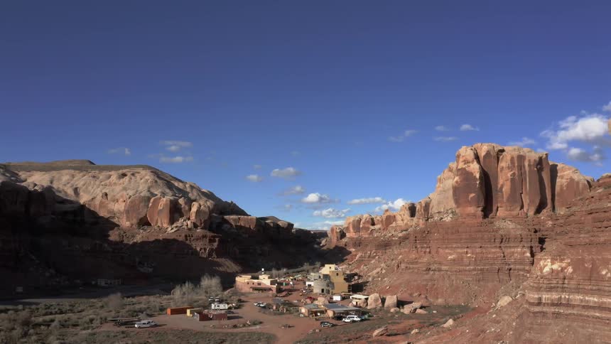 Cars on a road travel past a small town in the desert