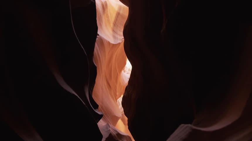 Sunlight is visible through the opening of the red rock canyon
