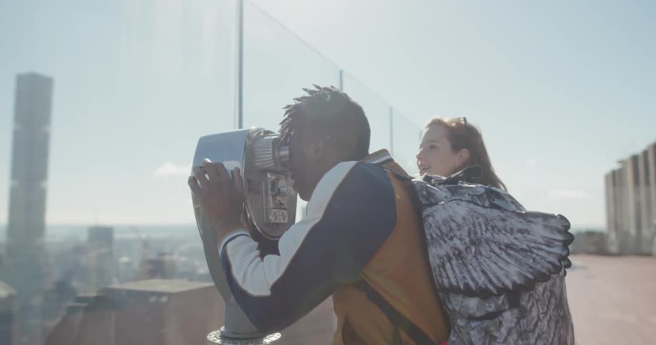 A man looks through a binocular on the skyscraper roof