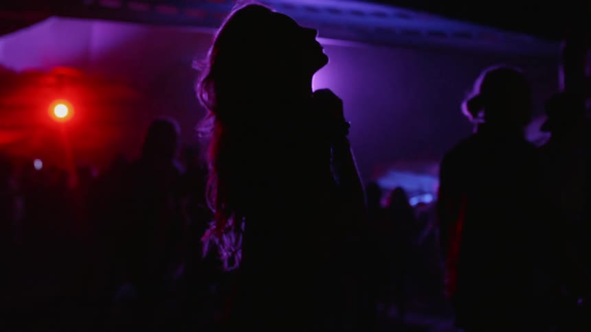 Woman dancing in a night club while man walk next to her