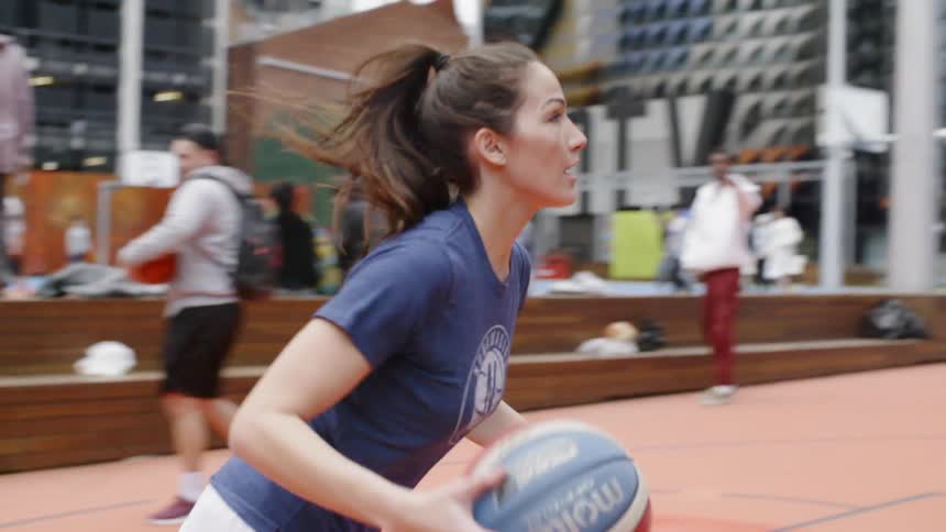 A woman drives the basketball towards the hoop