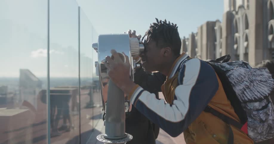 A man is looking through a binocular on the rooftop