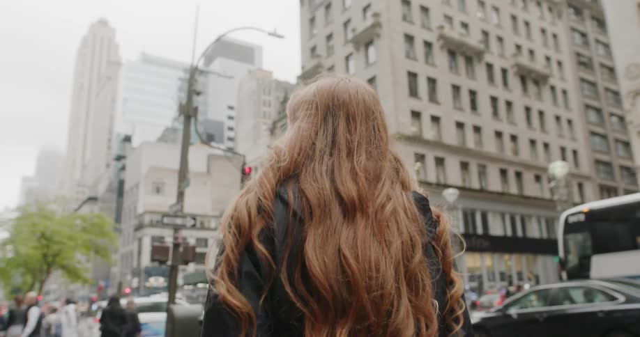 A woman walks down the city street towards crowds of people