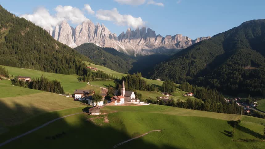 Sun shines down over several buildings at the base of mountains
