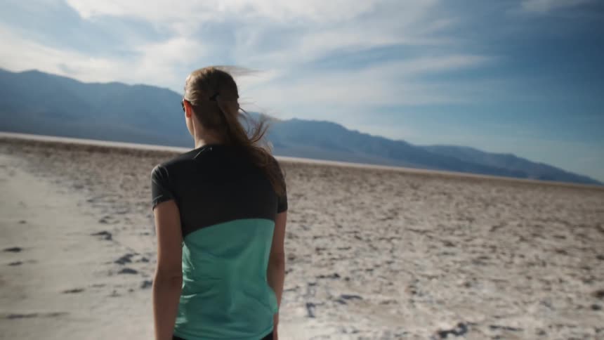 A woman walks in the desert as the wind blows