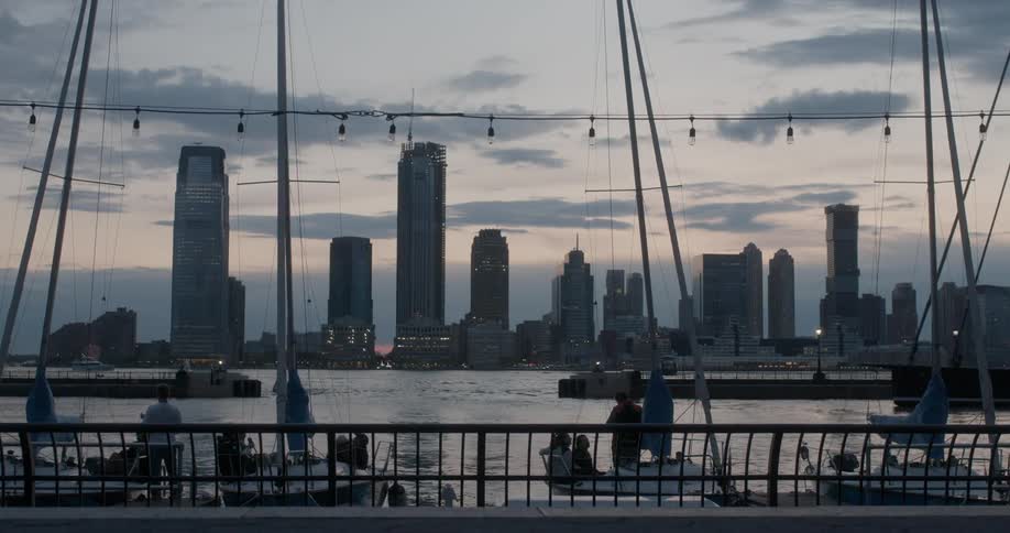 The tall buildings across the water have the sun setting behind