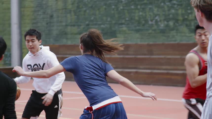 A girl is guarding a guy in a basketball game